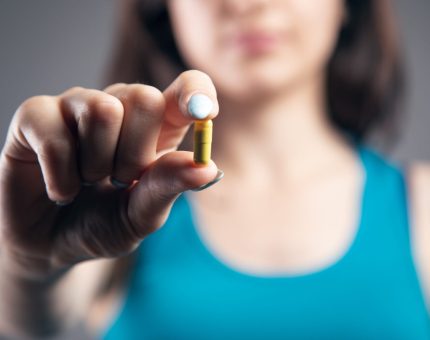 young woman holding a pill